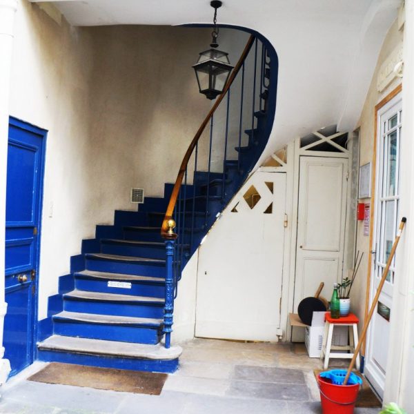 Hall d'immeuble avec un escalier bleu